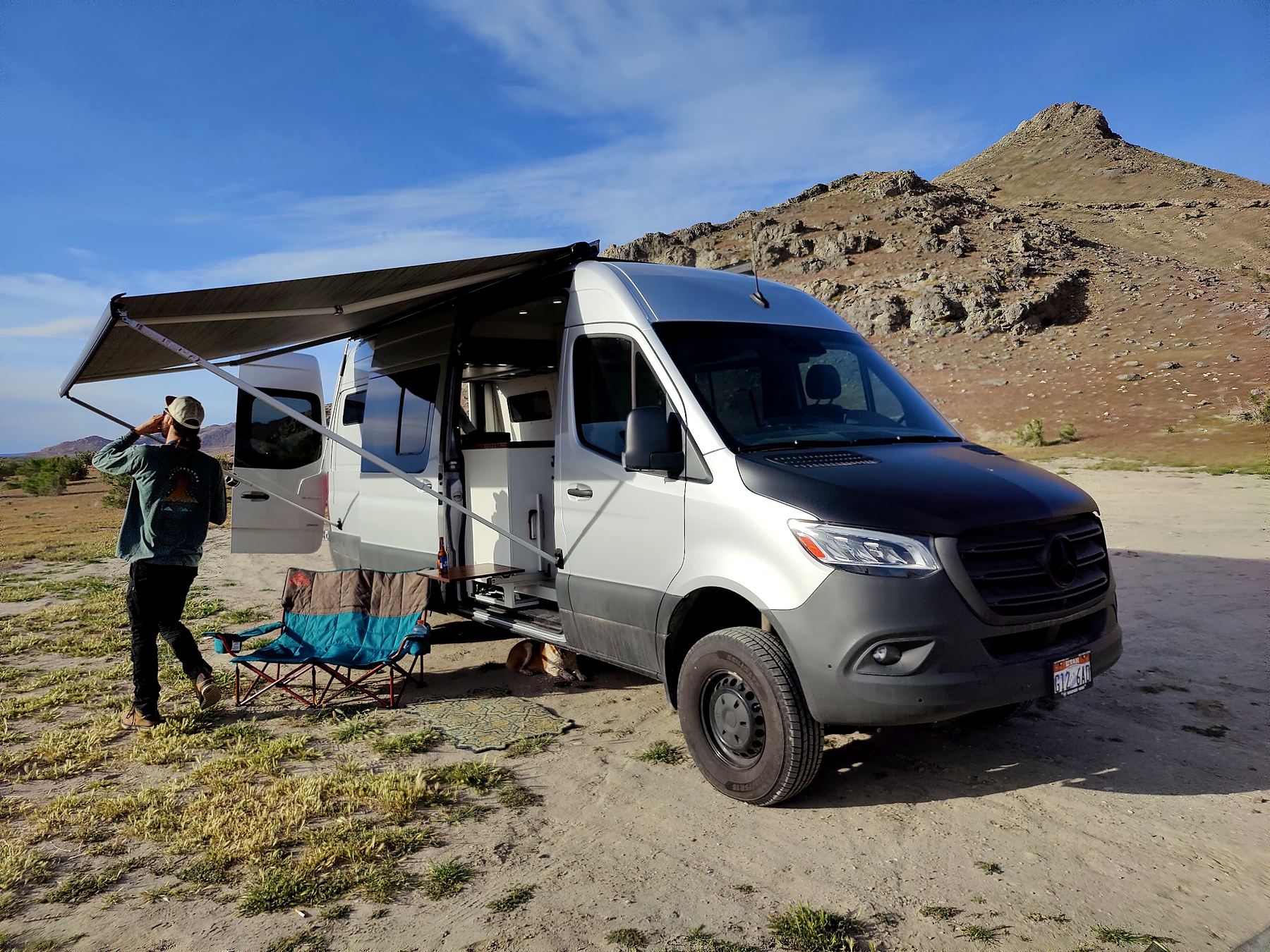 Fiamma awning rolled out over the side door of a silver Sprinter at camp