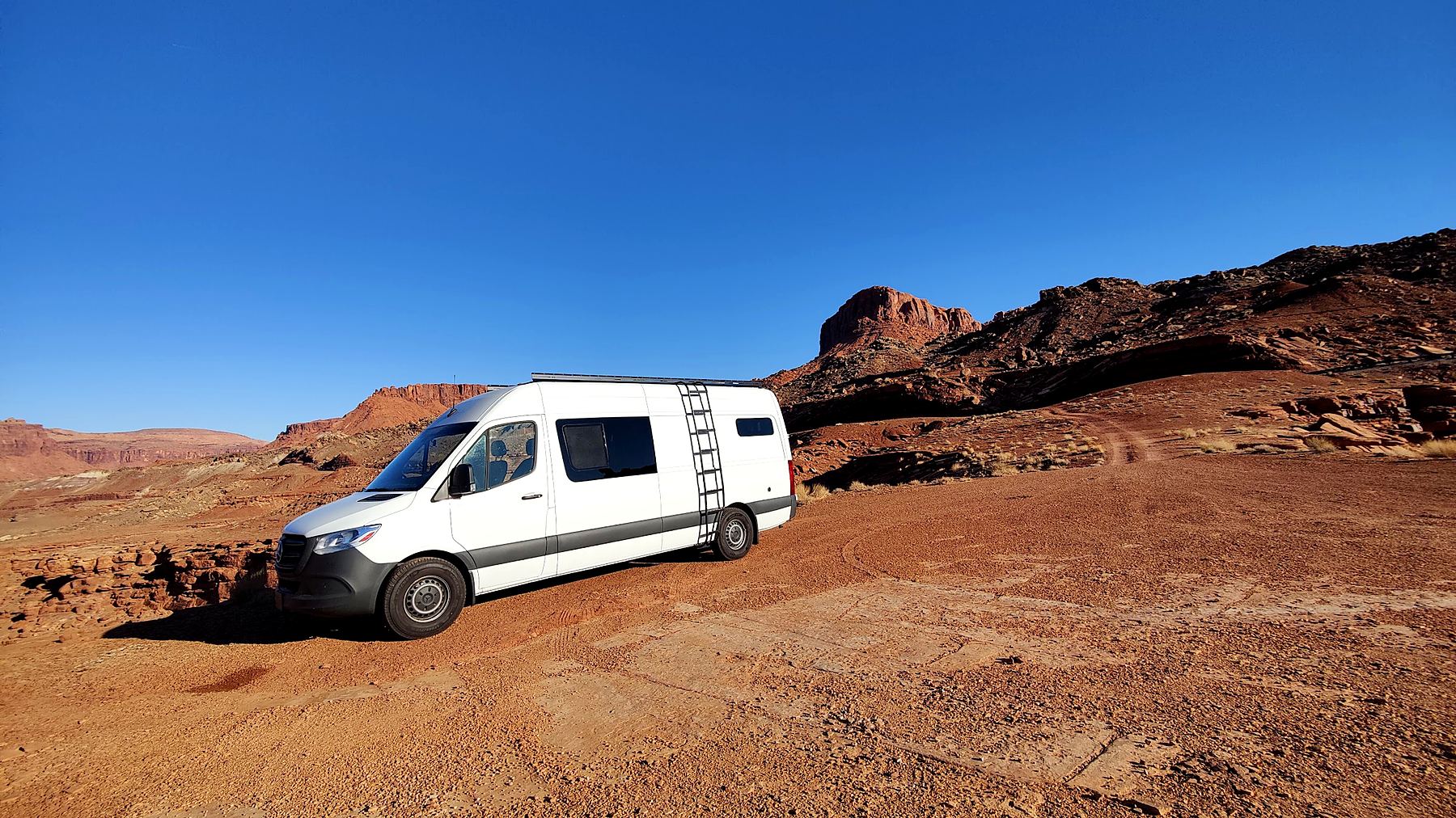 White Sprinter with added side windows parked in the desert