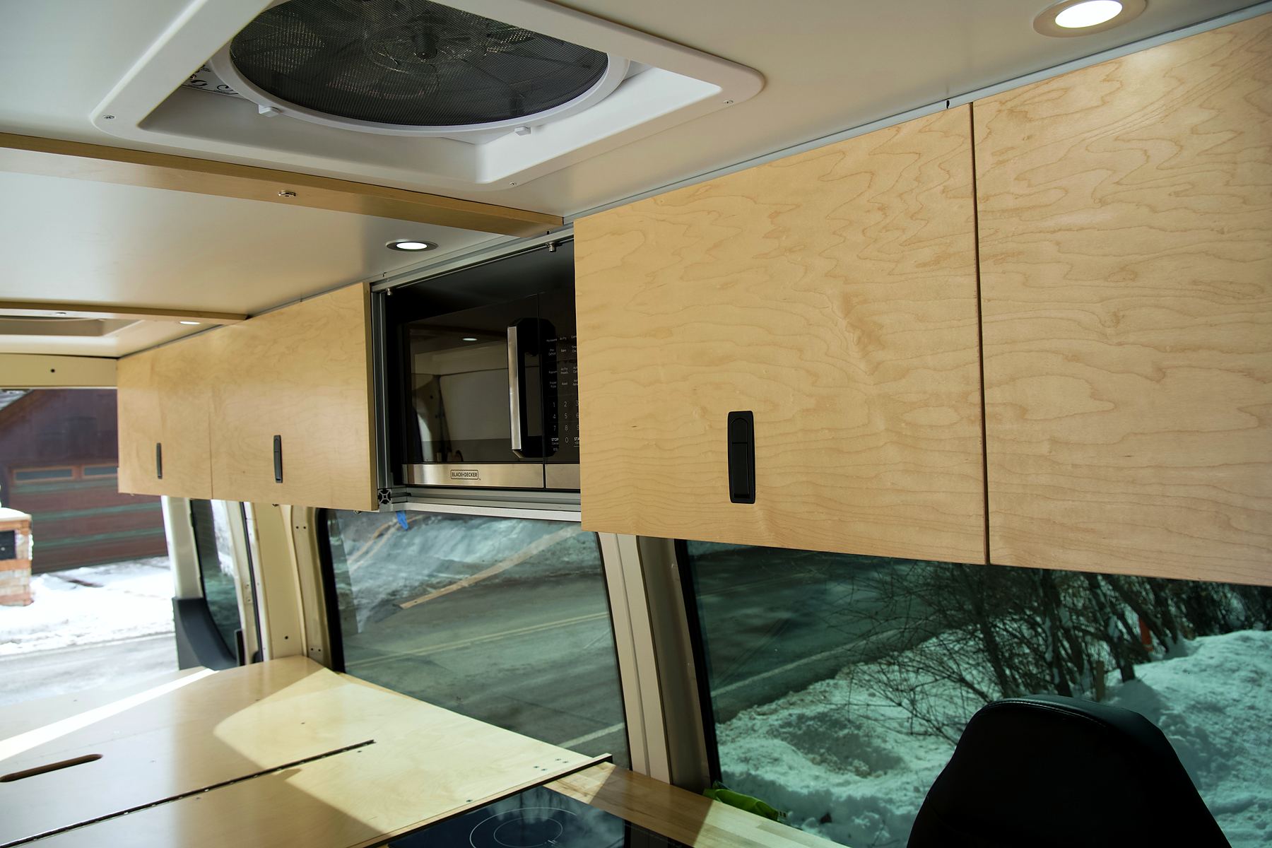 Maple upper cabinets with flush latches above the van windows